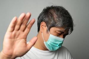 Kranker asiatischer Mann mit medizinischer Gesichtsmaske und Schulterschmerzen und Stress. konzept des schutzes pandemie coronavirus und atemwegserkrankungen foto
