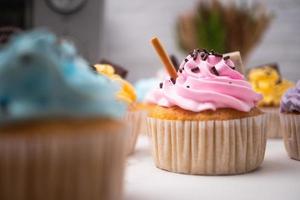 köstliche hausgemachte Cupcakes mit bunter Sahne und Topping mit Süßigkeiten und Schokoladenkeksen. hausgemachtes Herbstferiendessert foto