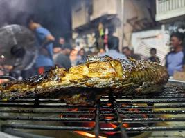 ein schließen oben von Fisch Sein gegrillt mit ein lodernd Feuer. zum Essen Hintergrund oder Hintergrund. Nein Menschen foto