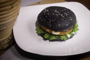 schließen oben Foto von das geöffnet schwarz Burger auf ein Weiß Teller ist höchst geeignet zum ein schnell Essen Speisekarte