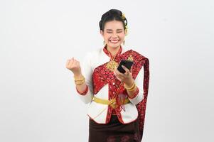 jung schön Frau Kleid oben im thailändisch Nord Region Pose mit Smartphone foto