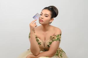 junge asiatische schöne braut, die in der hand mit kreditkarte postet foto