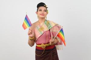 Porträt von jung Frau im thailändisch nordöstlich traditionell Kleidung halten Regenbogen Flagge foto