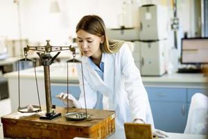 junge Forscherin, die das Gewicht der Mineralprobe im Labor misst foto