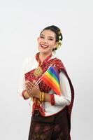 Porträt von jung Frau im thailändisch nordöstlich traditionell Kleidung halten Regenbogen Flagge foto