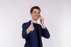 Porträt von glücklich gut aussehend Geschäftsmann reden durch Handy, Mobiltelefon Telefon und zeigen Finger beim Kamera isoliert Über Weiß Hintergrund foto