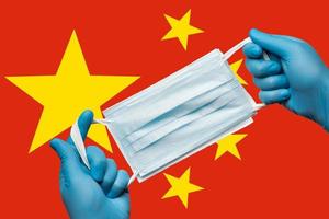 Medizin halten Atemwege Gesicht Maske im Hände im Blau Handschuhe auf Hintergrund Flagge von Menschen Republik von China prc foto