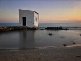 Fischerhütte bei Sonnenuntergang auf einigen Felsen nahe dem Strand in Calpe, Alicante foto