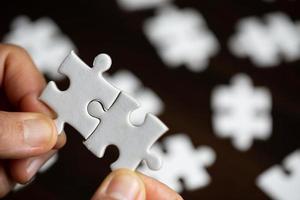 Geschäftsfrau-Personenhand, die Puzzleteilidee für Strategie und Lösung hält. Closeup Teil von zwei weißen Puzzles verbinden sich. konzept des gemeinsamen zusammenarbeitserfolgs teamwork-problem unternehmensteam foto