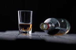 Stillleben mit Glas und Flasche Alkohol auf Holztisch foto