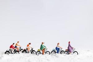 Miniaturreisende, die Fahrräder im Schnee, Winterhintergrundkonzept reiten foto