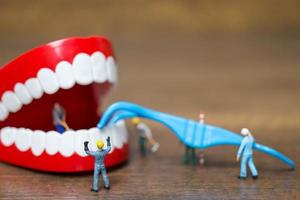 Miniaturarbeiter, die ein Zahn-, Gesundheits- und medizinisches Konzept reparieren foto