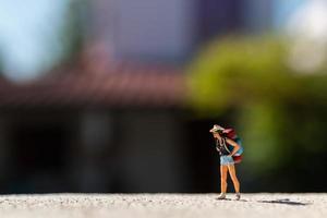 Miniaturreisender mit einem auf einer Straße stehenden Rucksack, Reisekonzept foto