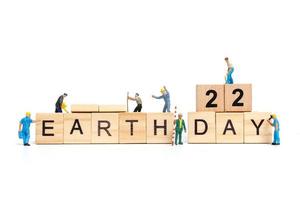 Miniaturarbeiter, die sich zusammenschließen, um das Wort Erde Tag 22 auf Holzklötzen, Tag der Erde Konzept zu bauen foto