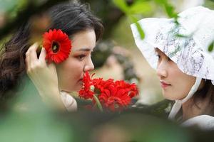 Frau, die Blumen in die Haare ihrer Freundin steckt foto