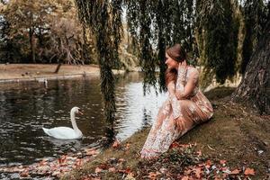 Frau, die ein Kleid trägt, das einen Schwan betrachtet foto