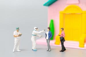 Miniaturmenschen mit ppe, die Patienten für eine Überprüfung auf Coronavirus zu Hause besuchen, Gesundheitskonzept foto