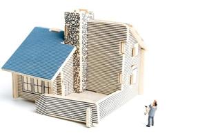 Miniaturpaar vor einem Holzhaus auf weißem Hintergrund foto