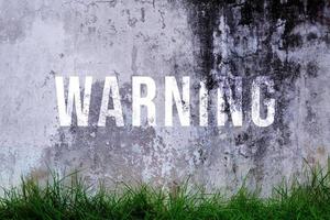 Warnung Text geschrieben mit gebrochen Zement Wand, Warnung Wort auf Straße. foto