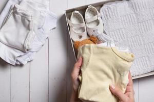 weiblich Hände stellen Kinder- Kleidung, Schuhe und Spielzeuge in ein Kasten. zweite Hand, Kleidung Recycling Konzept foto