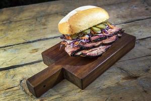 Brisket-Sandwich mit Gurke und Krautsalat auf Schneidebrett foto