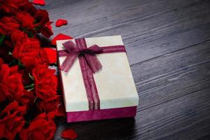 Geschenkbox und Rose auf hölzernem Hintergrund