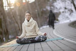 Eine junge sportliche Frau führt Yoga und Meditationsübungen im Freien durch foto