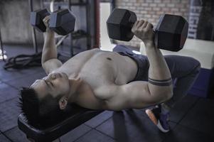porträt des asiatischen mannes großer muskel im fitnessstudio, thailänder, training für gute gesunde, körpergewichtstraining, fitness im fitnessstudio-konzept foto