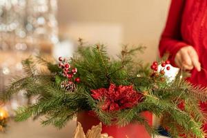 Mädchen sammelt einen Weihnachtsstrauß aus Tannenzweigen, Blumen und Christbaumschmuck foto