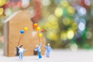 Miniaturleute, die Luftballons in einem Park mit einem bunten Bokehhintergrund, glücklichen Familienbeziehungen und sorglosem Freizeitkonzept halten foto