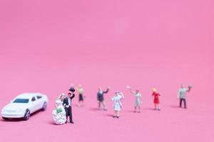 Miniaturhochzeit, eine Braut und ein Bräutigam auf einem rosa Hintergrund foto