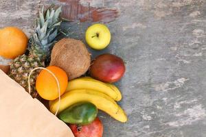 Papier Tasche mit Früchte und Gemüse auf alt hölzern Hintergrund. oben Sicht. foto