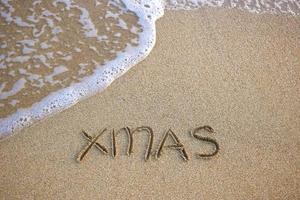 Weihnachten geschrieben auf sandig Strand Meer. oben Sicht. eben legen. foto