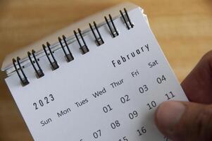 oben Aussicht von Hand umdrehen Februar 2023 Kalender. Kalender Konzept foto