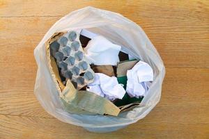 Müll Tasche mit Papier Müll auf hölzern Hintergrund. oben Sicht. foto