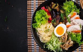 japanisch Ramen Suppe mit Huhn, Ei, Shimeji Pilze und Auberginen auf dunkel hölzern Hintergrund. Chanko Nabe, Sumo Suppe. oben Aussicht foto