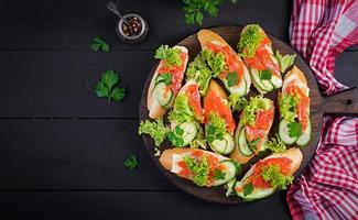 Tapas. gesalzen Lachs, Butter und Gurke Toast Sandwiches auf hölzern Tafel. oben Aussicht foto