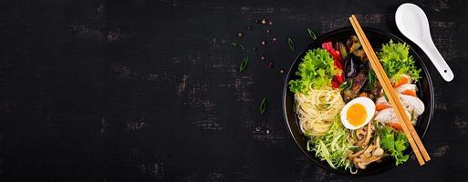 japanisch Ramen Suppe mit Huhn, Ei, Shimeji Pilze und Auberginen auf dunkel hölzern Hintergrund. Chanko Nabe, Sumo Suppe. Banner. oben Aussicht foto