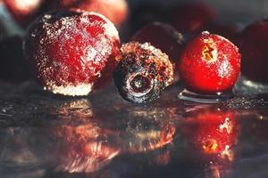 Nahansicht gefroren Beeren auf das Glas mit Betrachtung . gefroren Beeren auf ein dunkel Hintergrund Makro. Preiselbeeren Blaubeeren und Kirschen foto