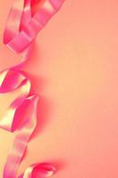 gebogen wellig Seide Satin- Rosa Band auf Rosa Hintergrund mit Kopieren Raum zum Text. Urlaub, Feier, Jubiläum, Geburtstag Geschenk Dekoration Konzept. Idee zum Gruß Karte, Verkauf Banner foto