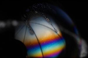 Makro Bild von Hälfte Seife Blase auf schwarz Hintergrund. schön psychedelisch Farbe. extrem Nahansicht foto