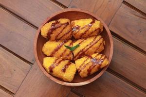 ein schließen oben von Banane Nuggets mit Schokolade Soße Belag serviert auf ein hölzern Schüssel. Essen Konzept Foto. foto