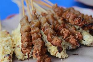 Foto von Hähnchen Satay beschichtet mit gebraten Ei und Hähnchen Darm Satay serviert mit rot Chili Soße. indonesisch Essen namens stillen Taichan. Essen Konzept Foto.