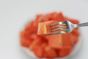 ein schließen oben von geschnitten Papaya erstochen mit ein Gabel foto