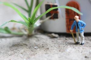 Miniatur Zahl von ein Großvater Wer ist warten im Vorderseite von das Haus. foto