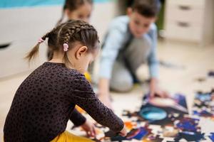 Kinder verbinden Puzzleteile in einem Kinderzimmer im Erdgeschoss zu Hause. lustige familienaktivität freizeit. foto