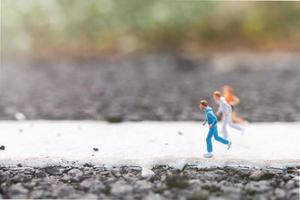 Miniaturmenschen, die auf einem Straßen-, Gesundheits- und Lebensstilkonzept laufen foto