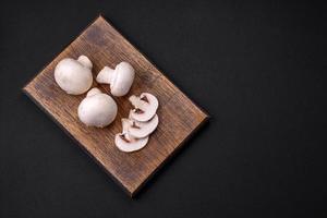 frisch roh Champignon Pilze auf ein hölzern Schneiden Tafel mit Gewürze foto