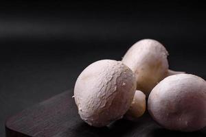frisch roh Champignon Pilze auf ein hölzern Schneiden Tafel mit Gewürze foto