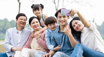 Bild von ein asiatisch Familie Sitzung zusammen auf das Gras beim das Park foto